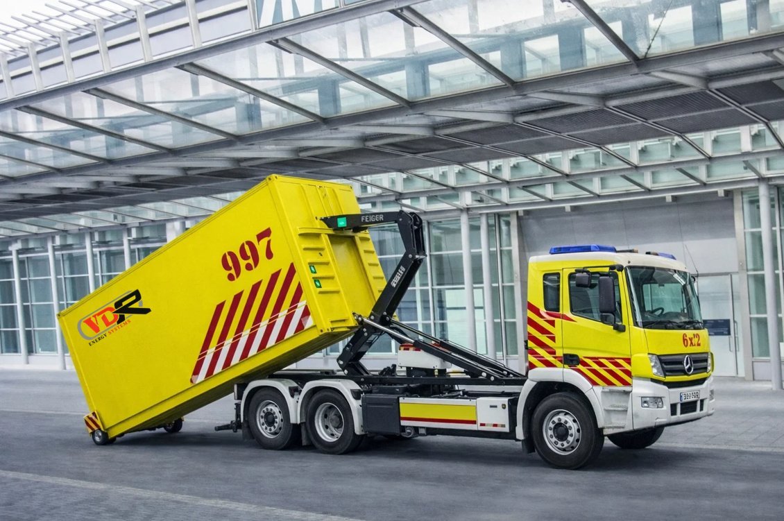 VDR Energy Systems hook-loader truck deploying yellow MPSS container at airport